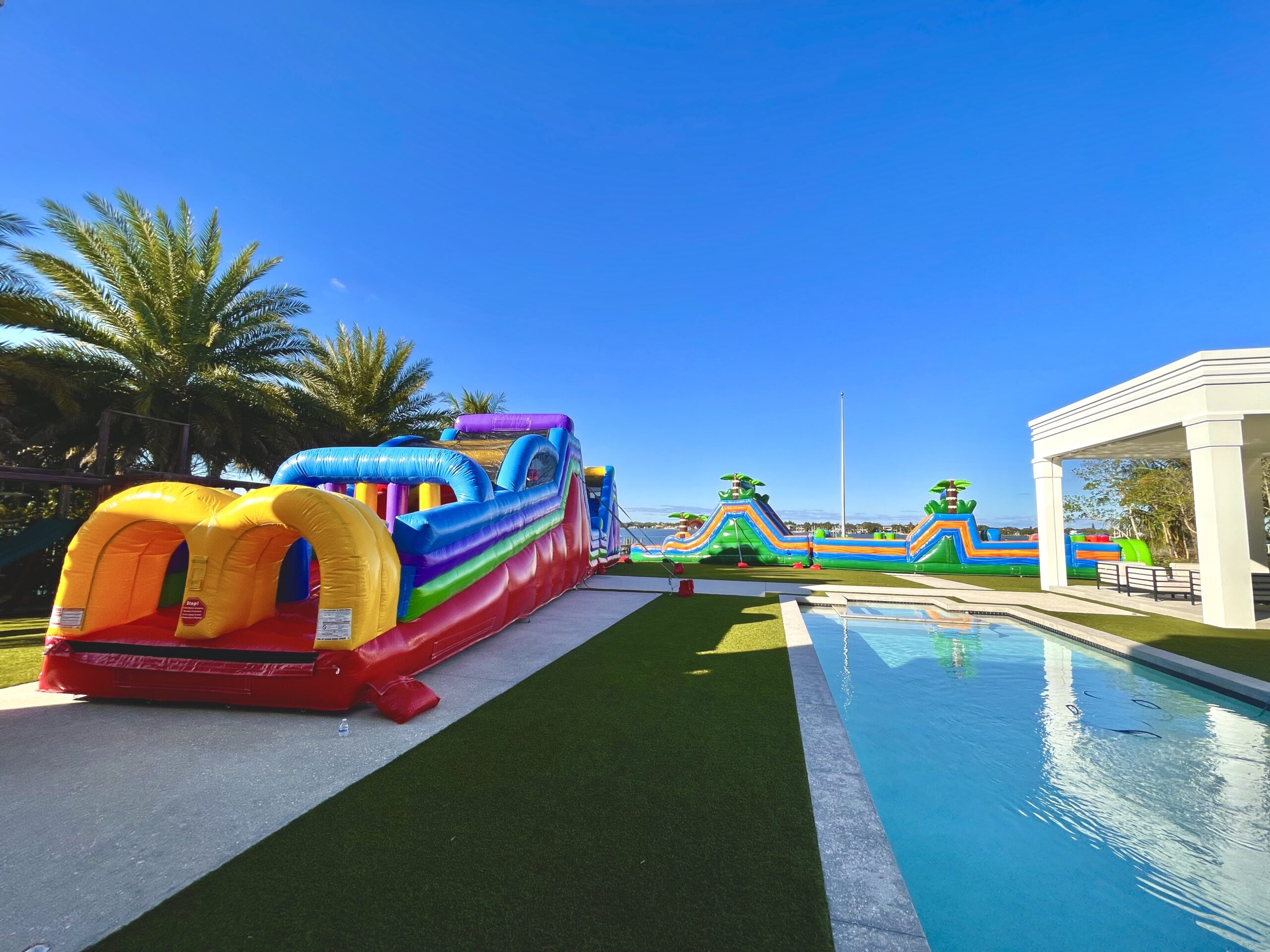 Inflatable water slide rental for 4th of July party in West Palm Beach FL – kids sliding into pool in backyard
